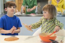 Children cooking in kitchen with parents on background — Stock Photo