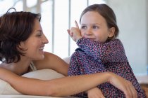 Donna sorridente con la figlia a casa — Foto stock
