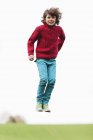 Porträt eines verspielten Jungen, der im Herbstfeld springt — Stockfoto