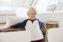 Portrait de heureux petit garçon aux cheveux blonds debout dans le salon — Photo de stock