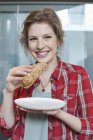 Портрет улыбающейся молодой женщины, поедающей сэндвич — стоковое фото