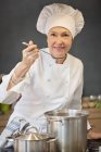 Retrato de mulher em traje de chef cozinhar comida na cozinha — Fotografia de Stock
