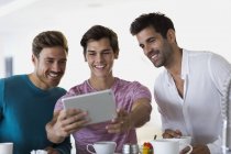 Крупним планом трьох щасливих молодих чоловіків, які приймають селфі з цифровим планшетом — стокове фото