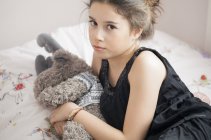 Serious teenage girl sitting on bed — Stock Photo