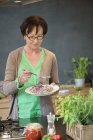 Seniorin verkostet Essen in Küche — Stockfoto