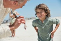 Uomo che mostra una medusa a suo nipote sulla spiaggia — Foto stock