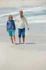 Мужчина гуляет со своим внуком по пляжу — стоковое фото