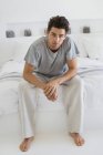 Портрет босоніж чоловіка, що сидить на ліжку — стокове фото
