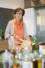 Porträt einer Seniorin beim Brotschneiden in der Küche — Stockfoto