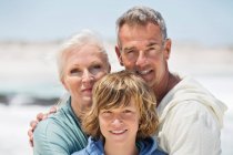 Retrato de un niño con sus abuelos en la playa - foto de stock