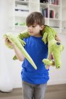 Junge spielt zu Hause mit ausgestopftem Krokodilspielzeug — Stockfoto