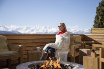 Woman sitting near fire pit on terrace of hotel, Crans-Montana, Swiss Alps, Switzerland — Stock Photo