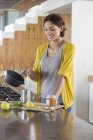 Lächelnde Frau bereitet in der Küche Kräutertee zu — Stockfoto