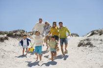 Familia feliz caminando en la playa de arena en verano - foto de stock