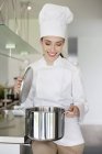 Felice chef donna che tiene la casseruola in cucina — Foto stock