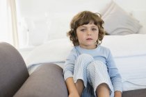Ritratto di bambino triste seduto sul letto — Foto stock