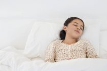 Маленькая девочка спит на белой кровати — стоковое фото