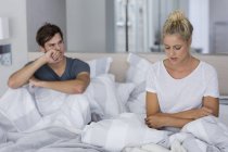 Junges Paar sitzt mit Beziehungsschwierigkeiten im Bett — Stockfoto