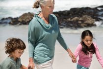 Mulher brincando com seus netos na praia — Fotografia de Stock