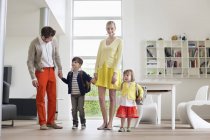 Casal feliz com crianças pequenas em pé no apartamento moderno — Fotografia de Stock