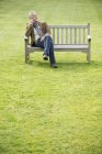 Elegant man sitting on bench in field and thinking — Stock Photo
