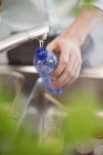 Male hand filling bottle with water in kitchen — Stock Photo