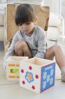 Linda niña jugando con cubos anidados en casa - foto de stock