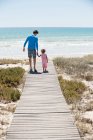 Homem com sua filha andando em um calçadão na praia — Fotografia de Stock