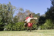 Petite fille jouant avec un avion en carton sur la pelouse — Photo de stock