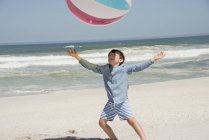 Мальчик играет на летнем пляже с красочным мячом — стоковое фото
