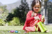 Girl picking up Easter eggs on lawn in nature — Stock Photo