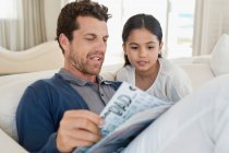 Man and his daughter reading a magazine — Stock Photo