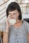 Retrato de jovem mulher bebendo copo de suco em casa — Fotografia de Stock