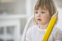 Милая маленькая девочка с большим карандашом — стоковое фото