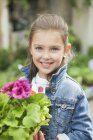 Retrato de niña sonriente sosteniendo una planta en maceta - foto de stock