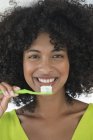 Portrait of woman with afro hairstyle brushing teeth — Stock Photo