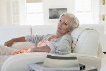 Relaxed woman sitting on couch and thinking — Stock Photo