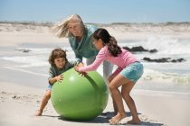 Жінка грає зі своїми онуками на пляжі — стокове фото