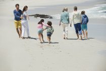 Familia feliz caminando en la playa de arena - foto de stock