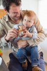 Mann füttert seinen Sohn am Küchentisch mit Brot — Stockfoto