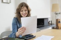 Woman sorting out bills at wooden table in modern apartment — Stock Photo