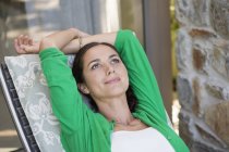 Thoughtful woman relaxing on lounge chair — Stock Photo