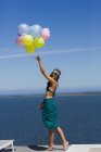 Счастливая стильная женщина, держащая воздушные шары на фоне голубого неба — стоковое фото