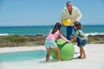 Чоловік грає зі своїми онуками на пляжі — стокове фото