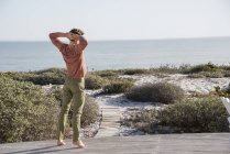 Giovane uomo in piedi sulla terrazza in legno e guardando il mare — Foto stock