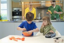 Bambina con macchinina guardando fratello che cucina in cucina — Foto stock