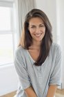 Portrait of smiling woman smiling in front of window — Stock Photo
