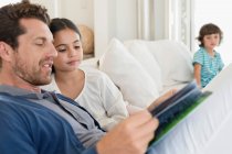 Mann liest Zeitschrift mit Tochter und Sohn im Hintergrund — Stockfoto