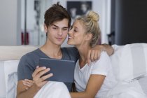 Молодая пара делает селфи с цифровым планшетом на кровати — стоковое фото