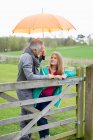 Чоловік стоїть зі своєю дочкою на фермі з парасолькою — стокове фото